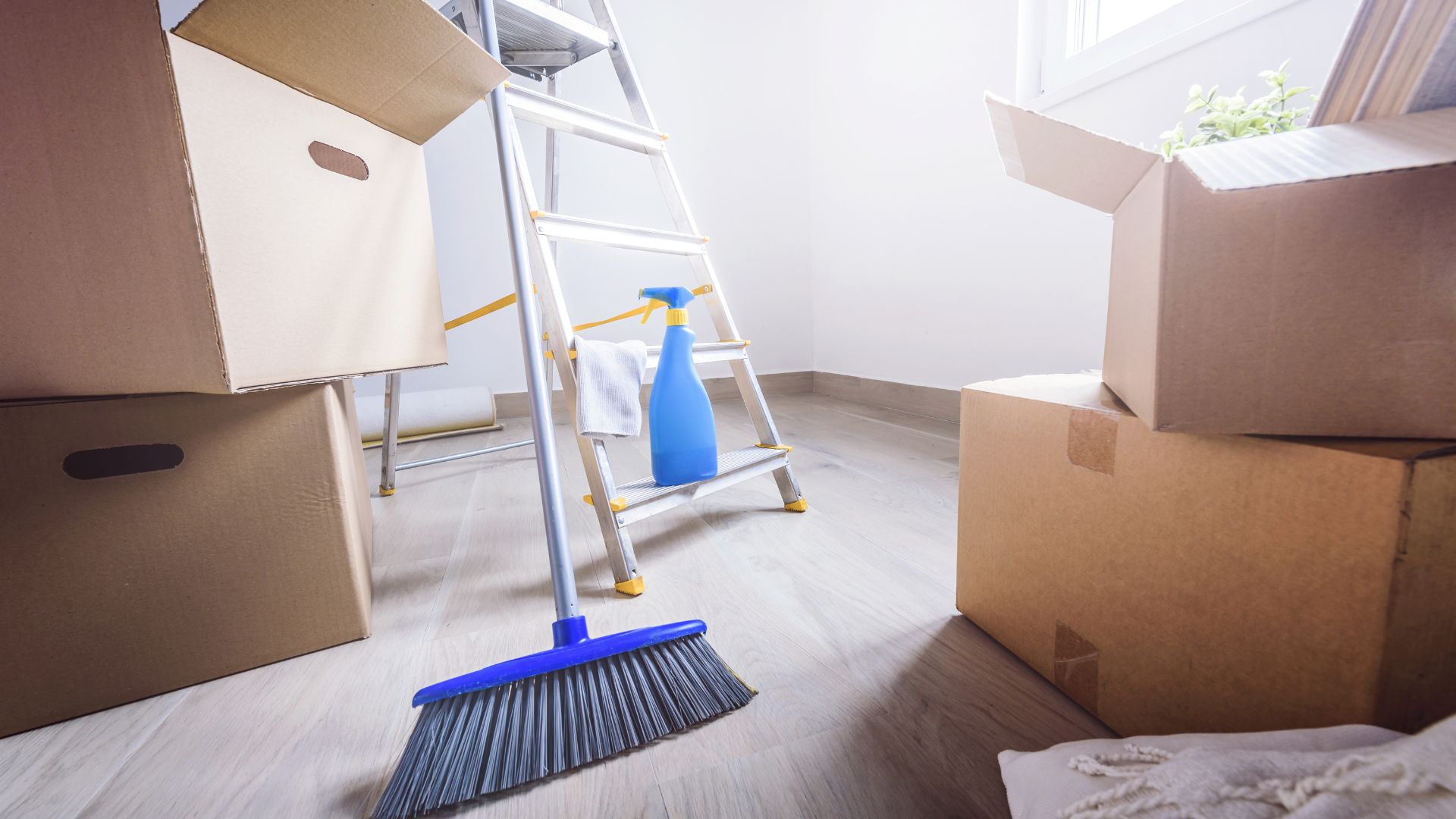 A room with boxes, a ladder, and a mop